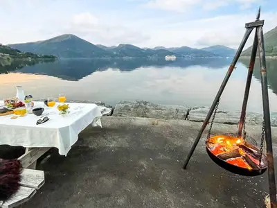 a dinner table with a hammock and a lake at 12 person holiday home in Davik in Davik