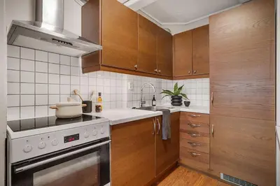a kitchen with wooden cabinets and a stove top oven at Leilighet - midt i sentrum! in Bergen