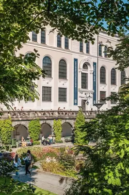 a building with people sitting in front of it at DINBNB Apartments l Historical Building I 100m To University Museum in Bergen