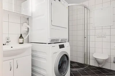 a white washing machine in a bathroom with a sink at DINBNB Apartments l Historical Building I 100m To University Museum in Bergen