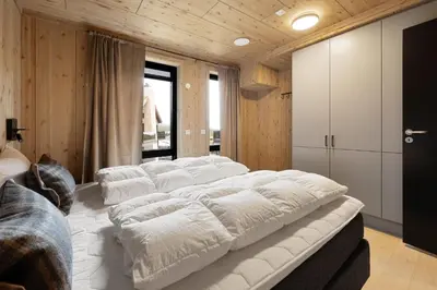 a large white bed in a room with wooden walls at Mosetertoppen Skistadion - Hafjell Ski Resort in Hafjell