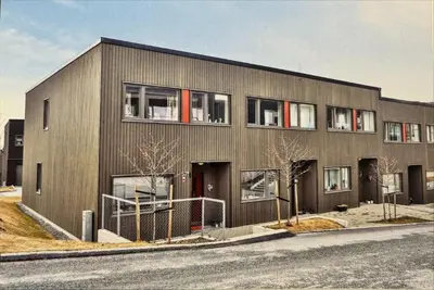 a gray building with red windows on the side of it at Rekkehus til leie under ski-VM in Heimdal