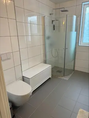 a white bathroom with a toilet and a shower at Rekkehus til leie under ski-VM in Heimdal