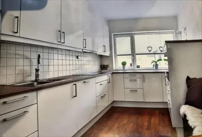 a kitchen with white cabinets and a large window at Rekkehus til leie under ski-VM in Heimdal