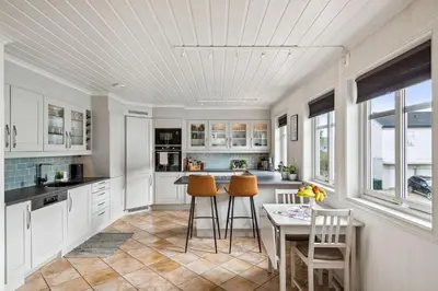 a kitchen with white cabinets and a table and chairs at Sentral enebolig til utleie under Ski VM 2025 in Trondheim