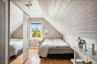 a attic bedroom with a bed and a window at Sentral enebolig til utleie under Ski VM 2025 in Trondheim