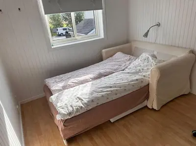 an unmade bed in a room with a window at Enebolig Trondheim syd in Trondheim