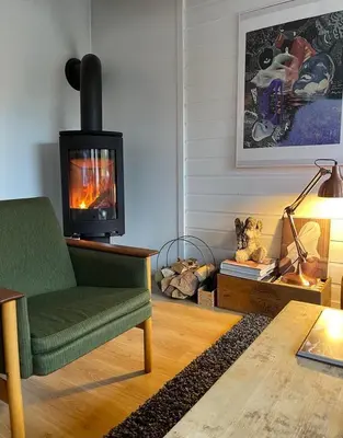 a living room with a fireplace and a green chair at Rekkehus til leie for ski-VM 2025! I nærheten av VM-arenaen! in Trondheim