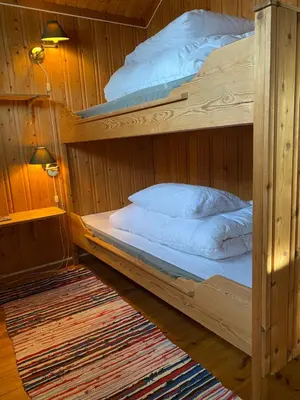 two bunk beds in a wooden room with a rug at Tørresvangen in Tynset