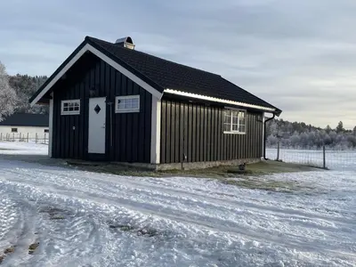 a black building with a white door in the snow at Tørresvangen in Tynset