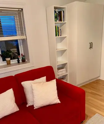 a red couch in a living room with a book shelf at Panoramic Fjord View near Bergen in Bergen
