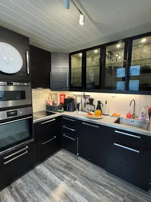 a kitchen with black cabinets and a clock on the wall at Prime location, 400 m from the town centre in Vossevangen