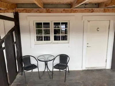 a patio with three chairs and a table and a window at Granmo Camping in Oppdal