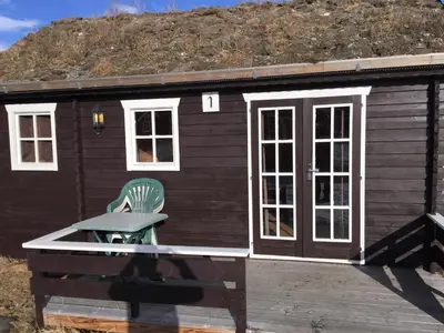 a tiny house with a green chair on a deck at Granmo Camping in Oppdal