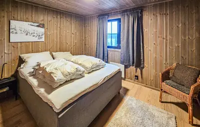 a bedroom with a bed and a chair and a window at Stunning Home In Vinje With Wifi in Trovatn