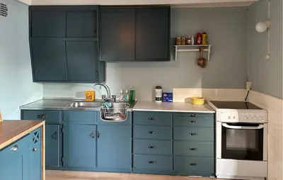 a small kitchen with blue cabinets and a sink at Cozy Home In Nerlandsøya Grunnkrets in Kvalsvik
