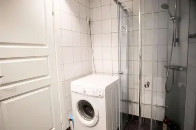 a bathroom with a washing machine and a shower at Beautiful Harbour Apartment With French Balcony in Bergen