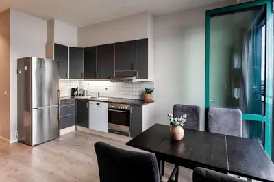 a kitchen with a table and a stainless steel refrigerator at Beautiful Harbour Apartment With French Balcony in Bergen