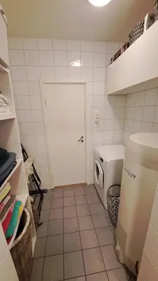 a small bathroom with a white door and a refrigerator at Ski in ski out 2bdr apartment in Trondheim