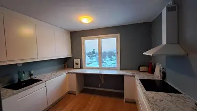 a kitchen with white cabinets and a large window at Ski in ski out 2bdr apartment in Trondheim