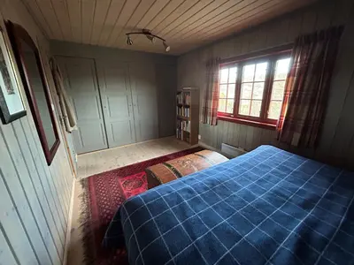 a bedroom with a blue bed and a window at Spacious cabin with beautiful Geilo views in Geilo