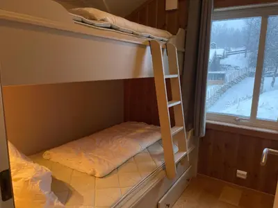 a bunk bed with a ladder in a room with a window at Bright 2-Bedroom With Terrace And Fireplace in Beitostøl