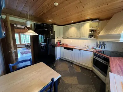 a kitchen with a table and a black refrigerator at Grand Log Cabin With Fireplace And 12-14 Beds in Beitostøl