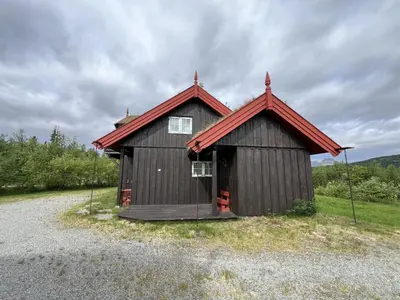 a small building with a red roof on a gravel road at Grand Log Cabin With Fireplace And 12-14 Beds in Beitostøl