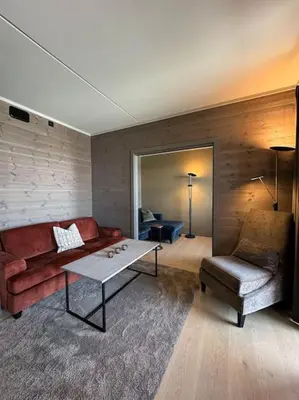 a living room with a couch and a table and a chair at Riddertunets utsikt til Mugnetind in Beitostøl