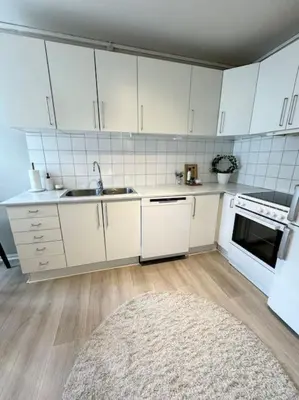 a kitchen with white cabinets and a white rug at Sentral og koselig leilighet i Trondheim in Trondheim