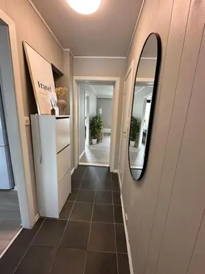 a hallway of a house with a mirror and a refrigerator at Sentral og koselig leilighet i Trondheim in Trondheim