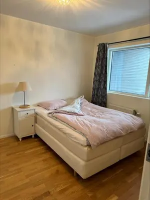 a bedroom with a bed with a lamp and a window at Skyttarbakken 57 in Heimdal