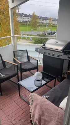 a patio with a grill and chairs on a porch at Leilighet nært Granåsen skisenter in Trondheim