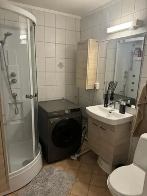 a bathroom with a shower sink and a washing machine at Leilighet nært Granåsen skisenter in Trondheim