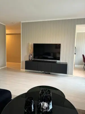 a living room with a black table and a flat screen tv at Leilighet nært Granåsen skisenter in Trondheim