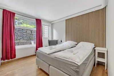 a bedroom with a bed with red curtains and a window at City Retreat in Bergen