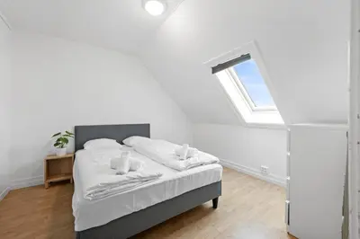 a white bedroom with a bed with a window at City center apartment with teracce in Bergen