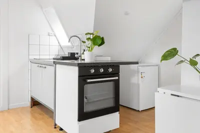 a kitchen with a black stove and white cabinets at City center apartment with teracce in Bergen