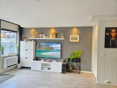 a living room with a tv and a white entertainment center at Exclusive three-story villa near the ski center in Trondheim