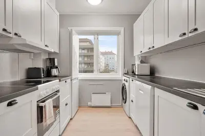 a kitchen with white cabinets and a window at Dinbnb Apartments l Free Parking l 5 Min From Torget l Nearby Coast I Newly Furnished in Bergen