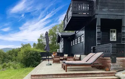 a deck with chairs and an umbrella on a house at Nice Home In Oppdal With Sauna in Oppdal