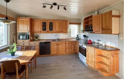 a kitchen with wooden cabinets and a table and a dining room at Beautiful Home In Vestre Gausdal in Vestre Gausdal