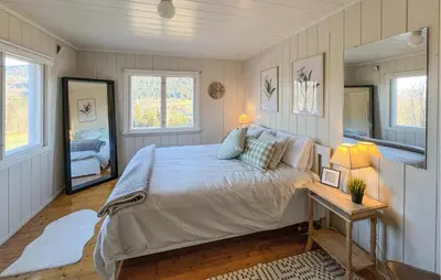 a bedroom with a bed and a table and two windows at Beautiful Home In Vestre Gausdal in Vestre Gausdal