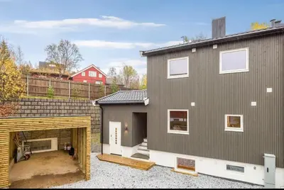 a large gray house with a garage and a red house at Flott bolig til VM! Gåavstand in Trondheim