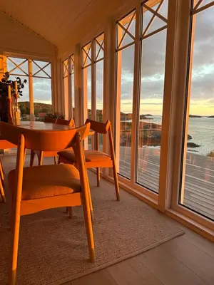 a dining room with a table and chairs and windows at Paradise by the Seaside in Hitra