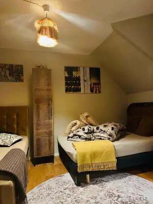 a bedroom with two beds and a chandelier at Historical house with view and separate entrance in Ålesund