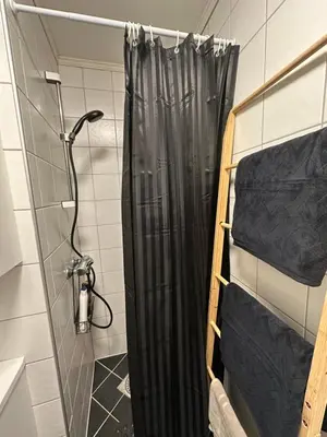 a shower with a black shower curtain in a bathroom at Historical house with view and separate entrance in Ålesund