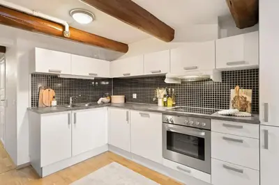 a kitchen with white cabinets and stainless steel appliances at Charming Loft, High Ceiling !Modern & Central, Free private Parking 7 min walking ! in Trondheim