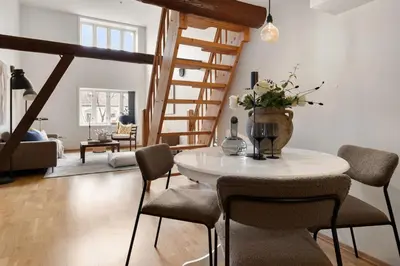 a living room with a table and chairs and a staircase at Charming Loft, High Ceiling !Modern & Central, Free private Parking 7 min walking ! in Trondheim