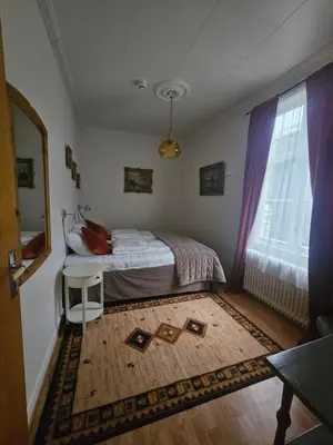 a small bedroom with a bed and a window at Eides Hotel in Høyanger